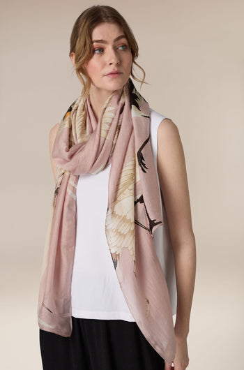 A woman wearing a white top and black skirt with an art deco Moon Phases Scarf looking to the side.