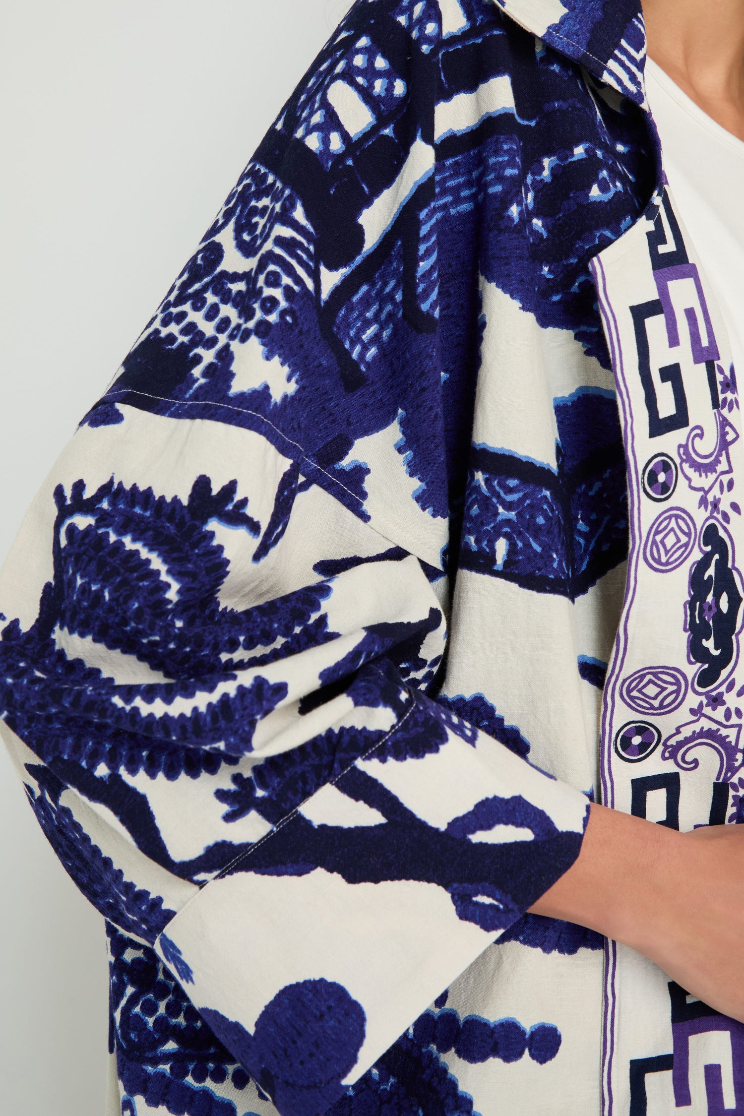 Wearing the Willow Print Summer Coat, a lightweight summer layer with bold blue abstract and geometric designs, partially visible from shoulder to mid-torso.