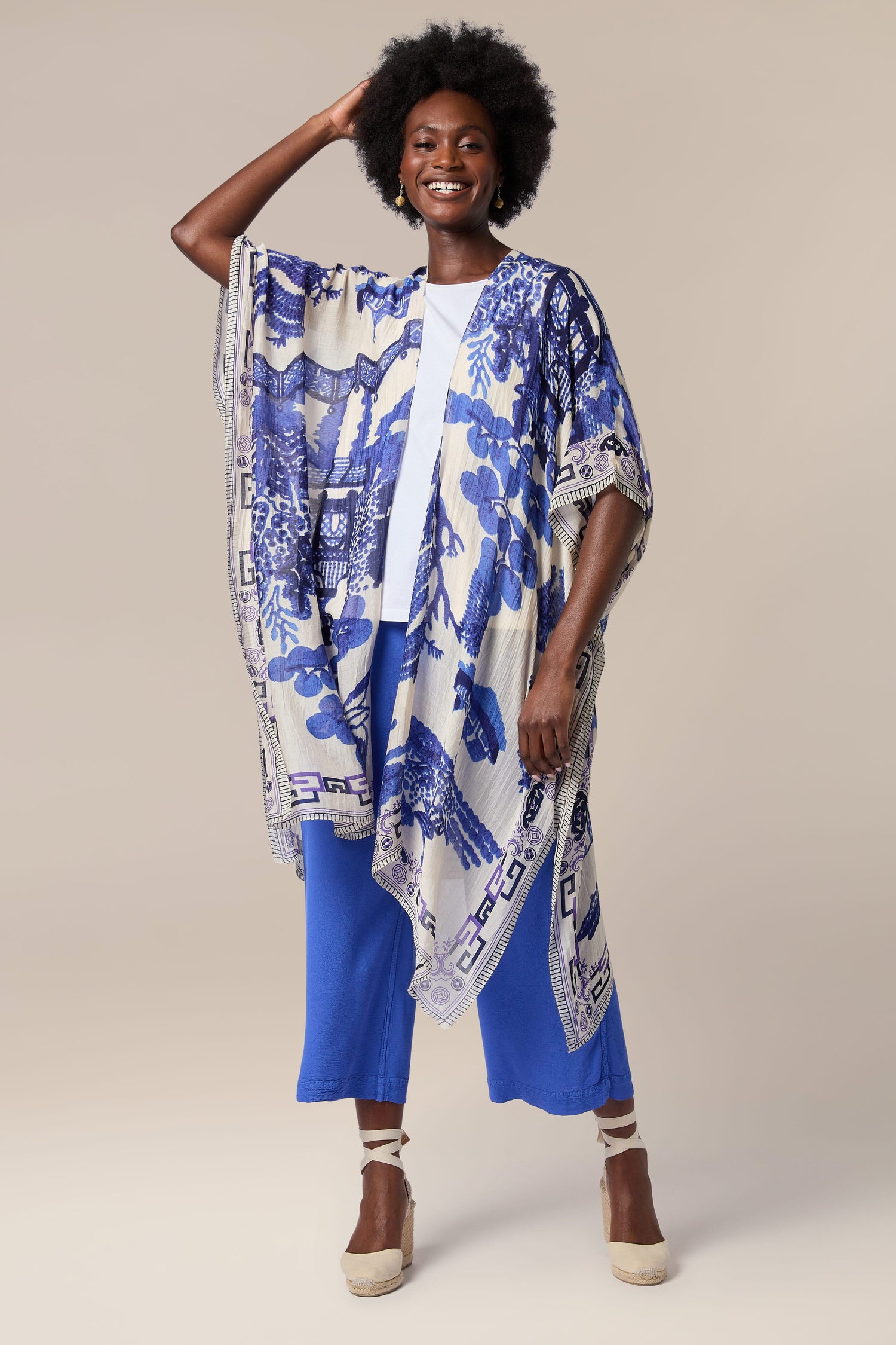 A woman wearing a blue kimono, also known as a Willow Throwover, adorned with Indian textiles.