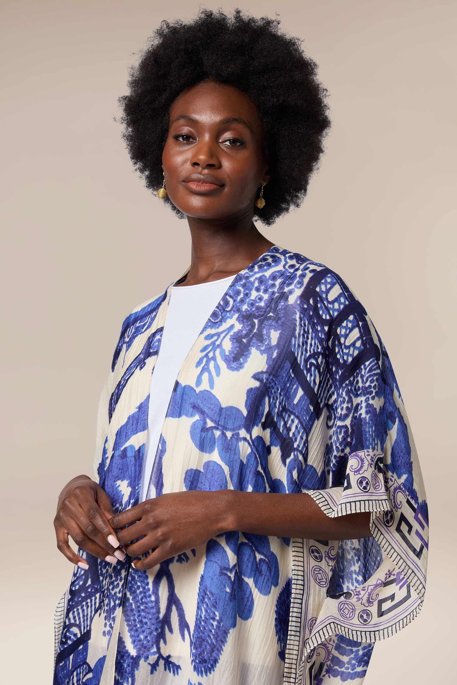 A woman wearing a blue and white printed Willow Throwover, inspired by textiles from India.