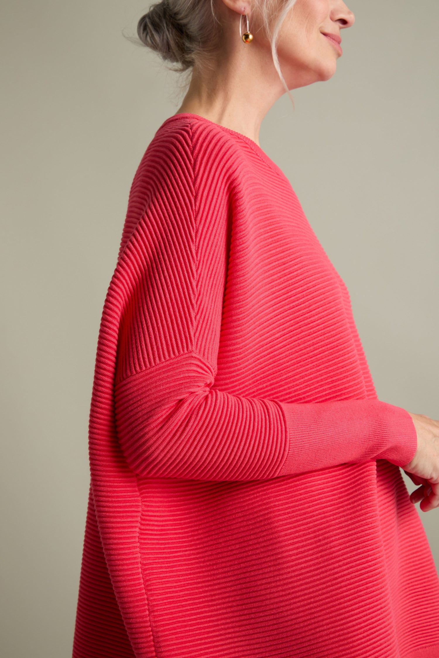 A woman is shown in profile, wearing an elegant Ribbed Jumper. Her hair is styled in a chic gray updo, and the depiction captures her from her shoulders to mid-thigh.