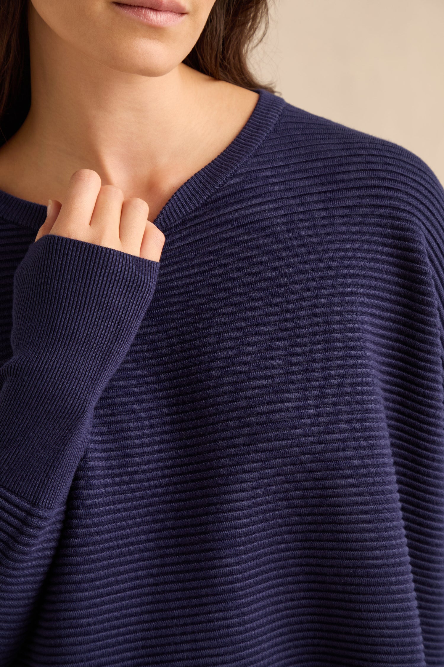 A woman wearing the Navy Ribbed Jumper holds the collar with her left hand. The image is cropped from her nose down to her torso.