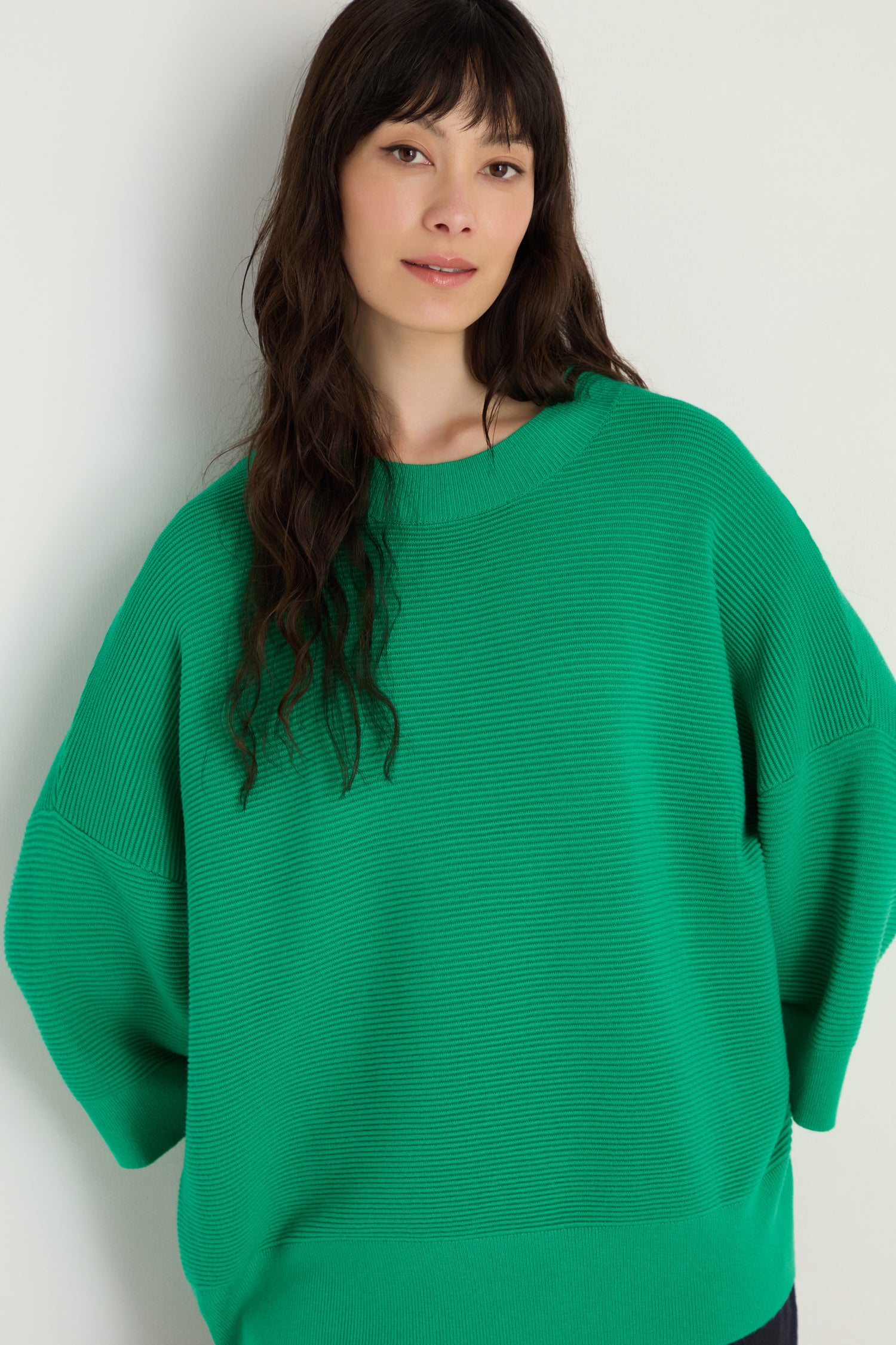 A woman with long dark hair wears the Wide Sleeve Ribbed Top, which features wide sleeves and a boxy silhouette, standing against a neutral background.