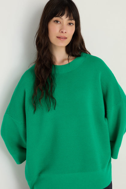 A woman with long dark hair wears the Wide Sleeve Ribbed Top, which features wide sleeves and a boxy silhouette, standing against a neutral background.