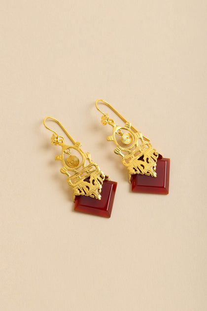 Gold-Plated Carnelian Drop Earrings featuring intricate designs and square reddish-brown stone accents, shown on a beige background.