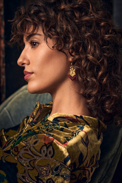 A person in profile wearing a Gold-Plated Carnelian Drop earring featuring a dark red stone.