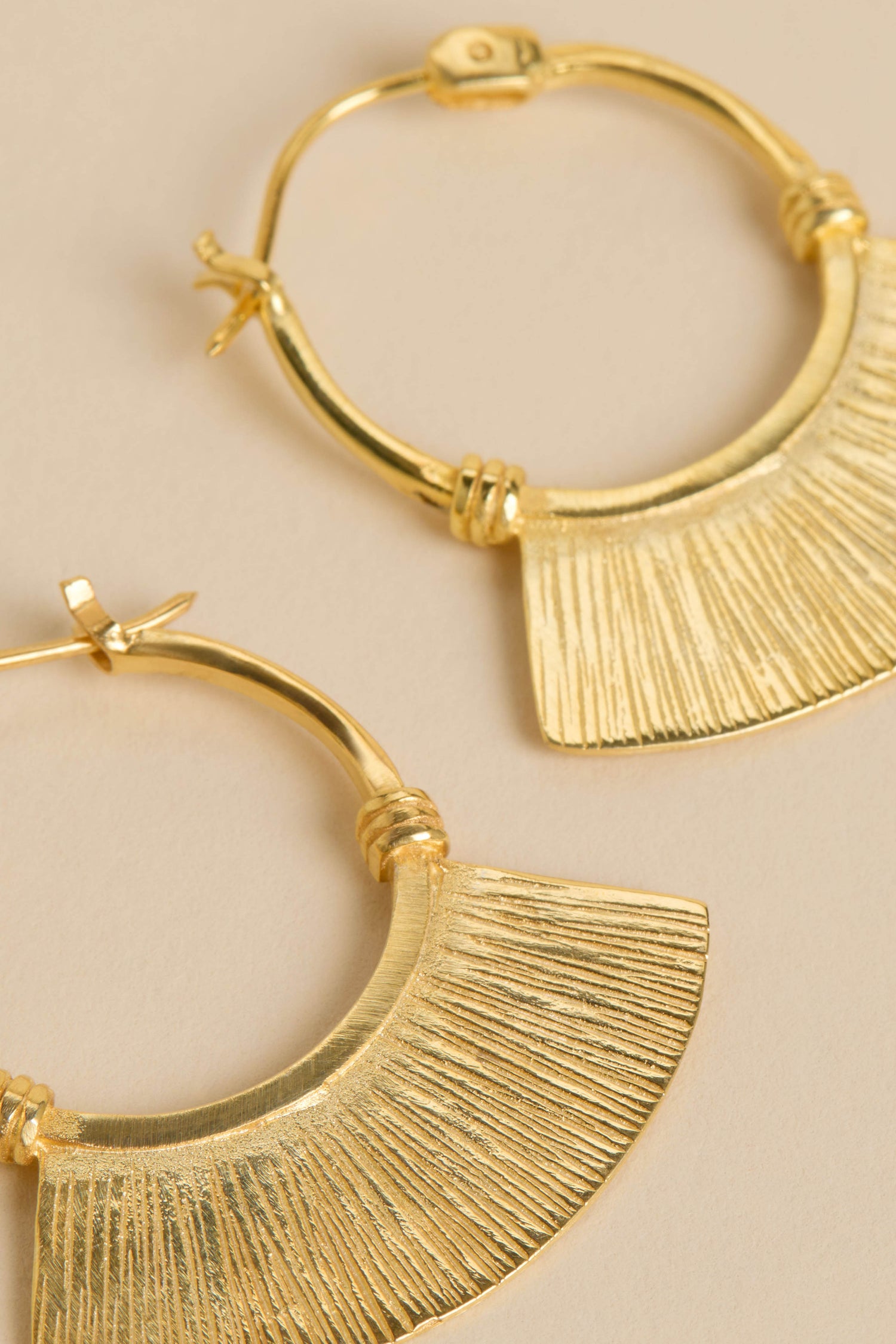 The Gold-Plated Fan Hoop Earrings feature textured hoops with fan-shaped pendants, showcased against a neutral backdrop.