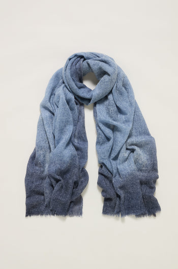 The Night Sky Gradient Cashmere Scarf, featuring a soft, textured fabric and lightweight feel, is displayed flat on a light background to highlight its delicate blue gradient design.