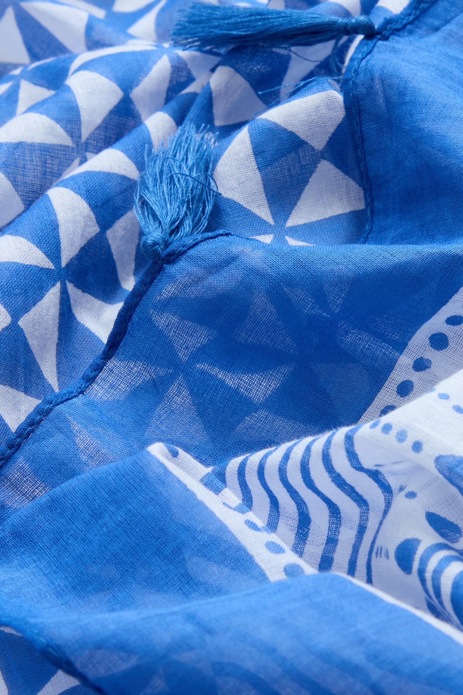 Close-up of the Cobalt Tassel Cotton Scarf, showcasing its blue and white geometric print and delicate tassel edging along the seam.