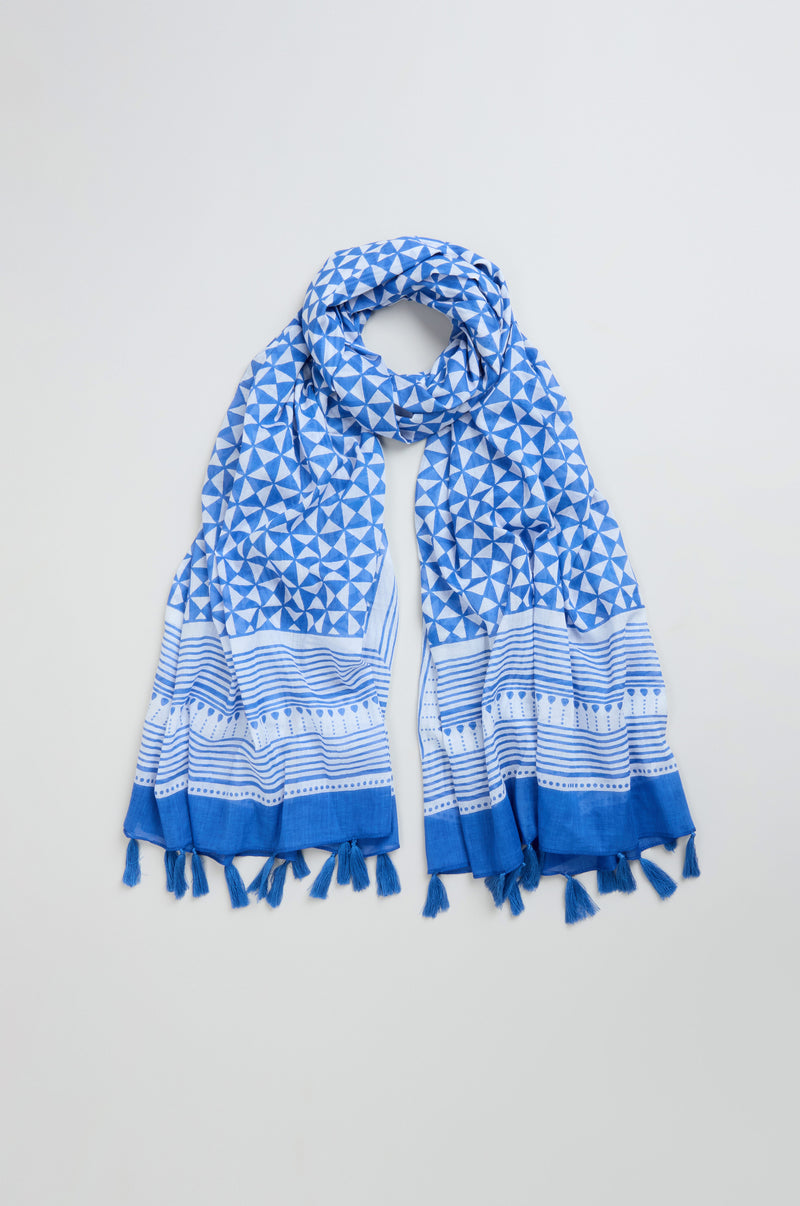 The Cobalt Tassel Cotton Scarf, featuring a bold blue and white geometric pattern and tasseled ends, is laid out flat on a light background.