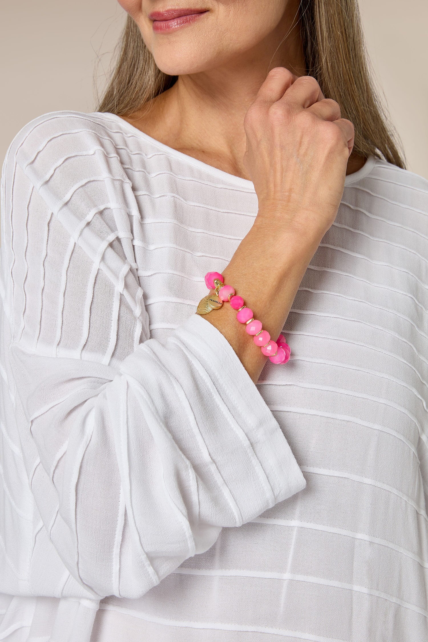 A modern traveller wearing a white shirt and Brazilian Agate Beaded Shell Bracelet by Pranella.