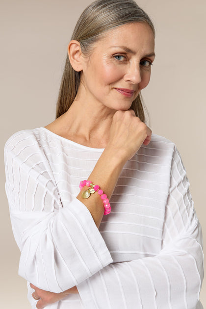 A modern traveller wearing a white shirt and Brazilian Agate Beaded Shell Bracelet.