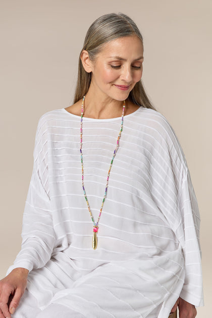 A woman wearing a vibrant Sherbet Beaded Pearl Pendant necklace.