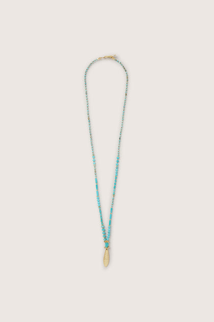 A handcrafted Turquoise Bead Gold Pendant with a gold charm.