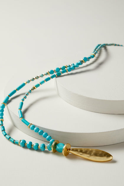 A handcrafted Turquoise Bead Gold Pendant adorned with turquoise beads and a gold plated pendant.