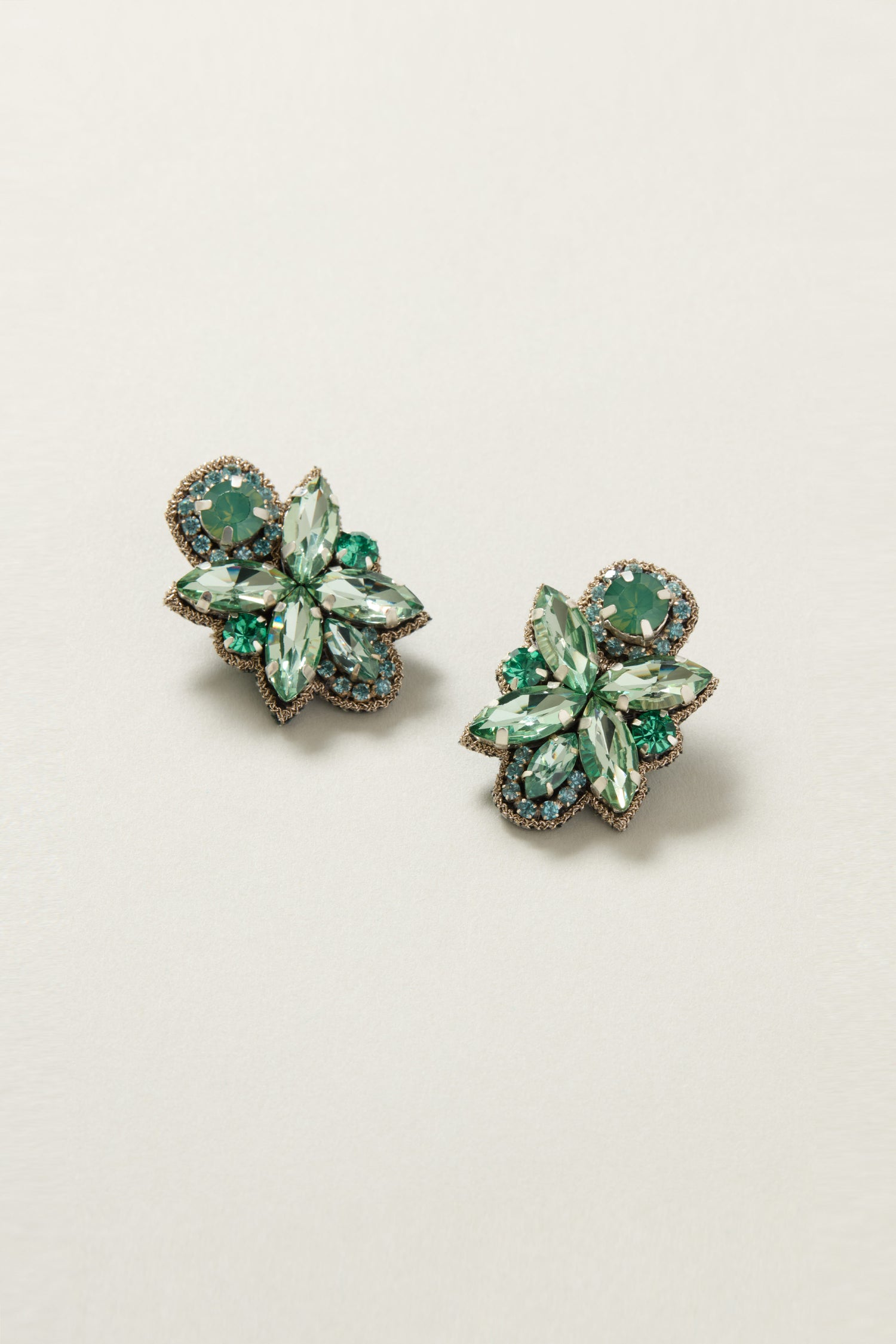 A pair of Hand Beaded Petal Earrings embellished with green gemstones and gold trim, showcased against a soft backdrop.