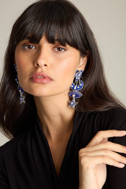 A woman with long, dark hair, dressed in a black top, gazes into the camera while wearing ornate blue and silver Celestial Hand Beaded Earrings.