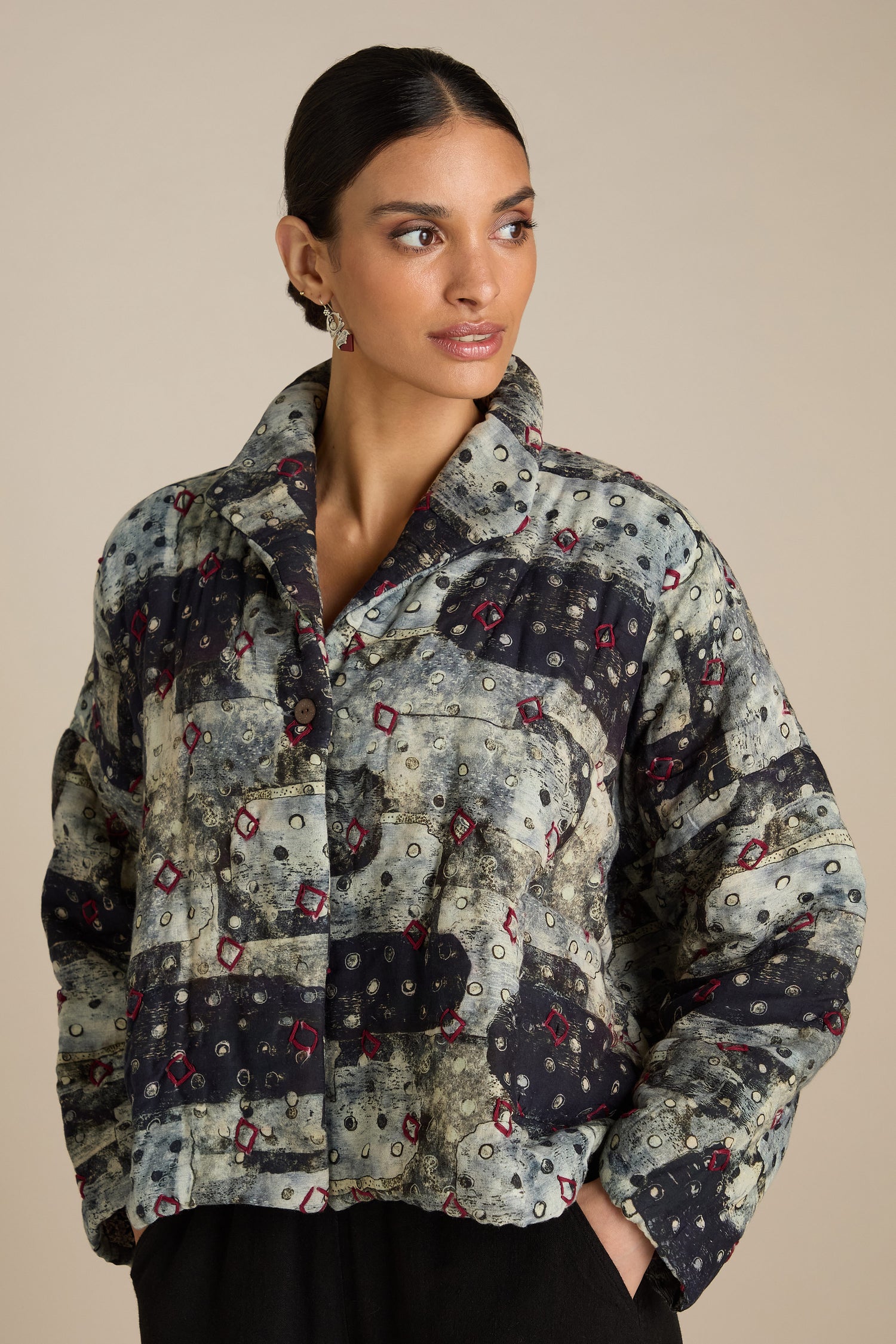 A person with dark hair pulled back wears a Padded Embroidered Cotton Jacket, standing against a plain background, looking off to the side.