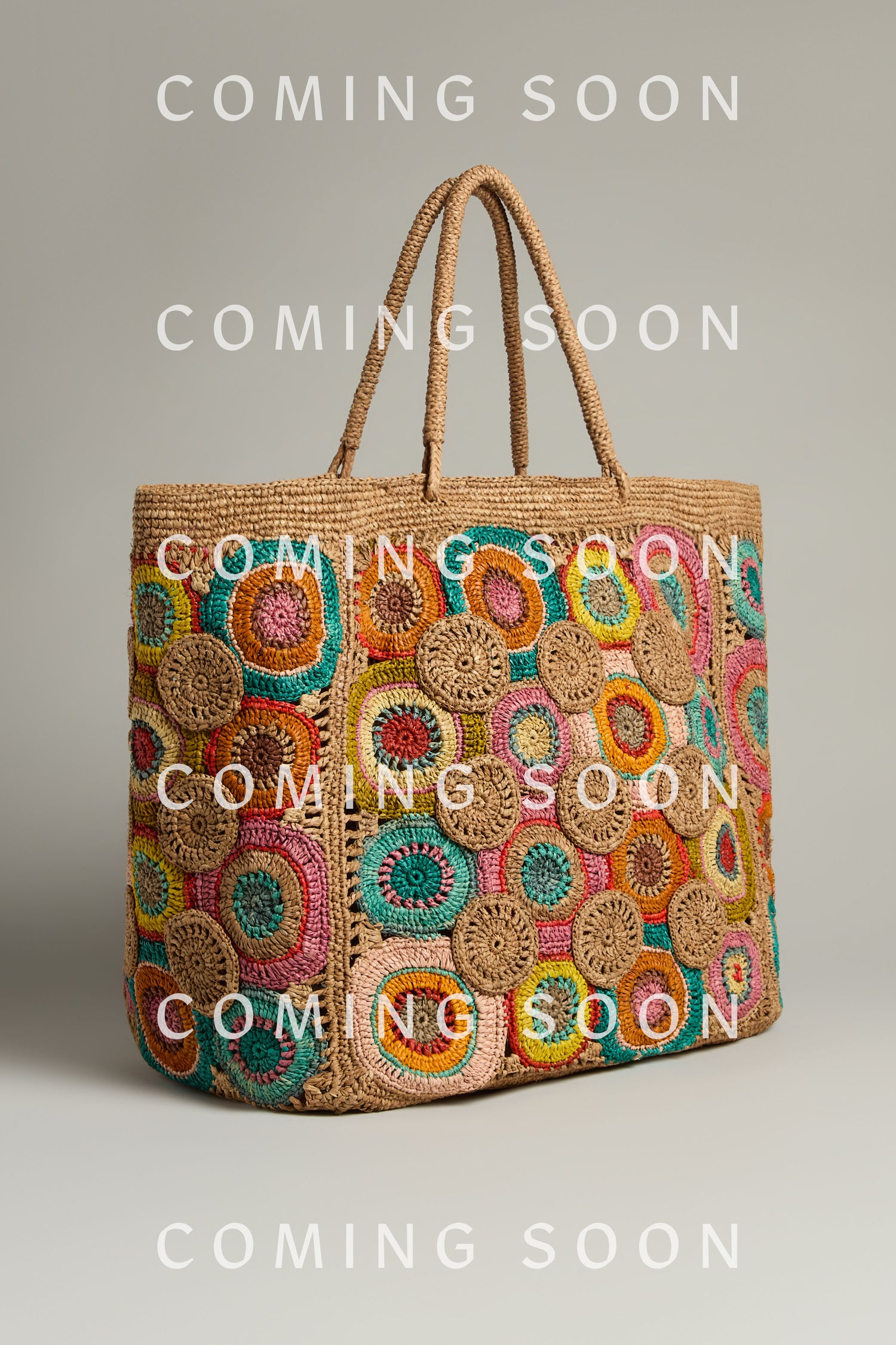 The vivid Handwoven Circles Raffia Bag, featuring circular designs and dual handles, pops against a simple background. Text reads "COMING SOON.