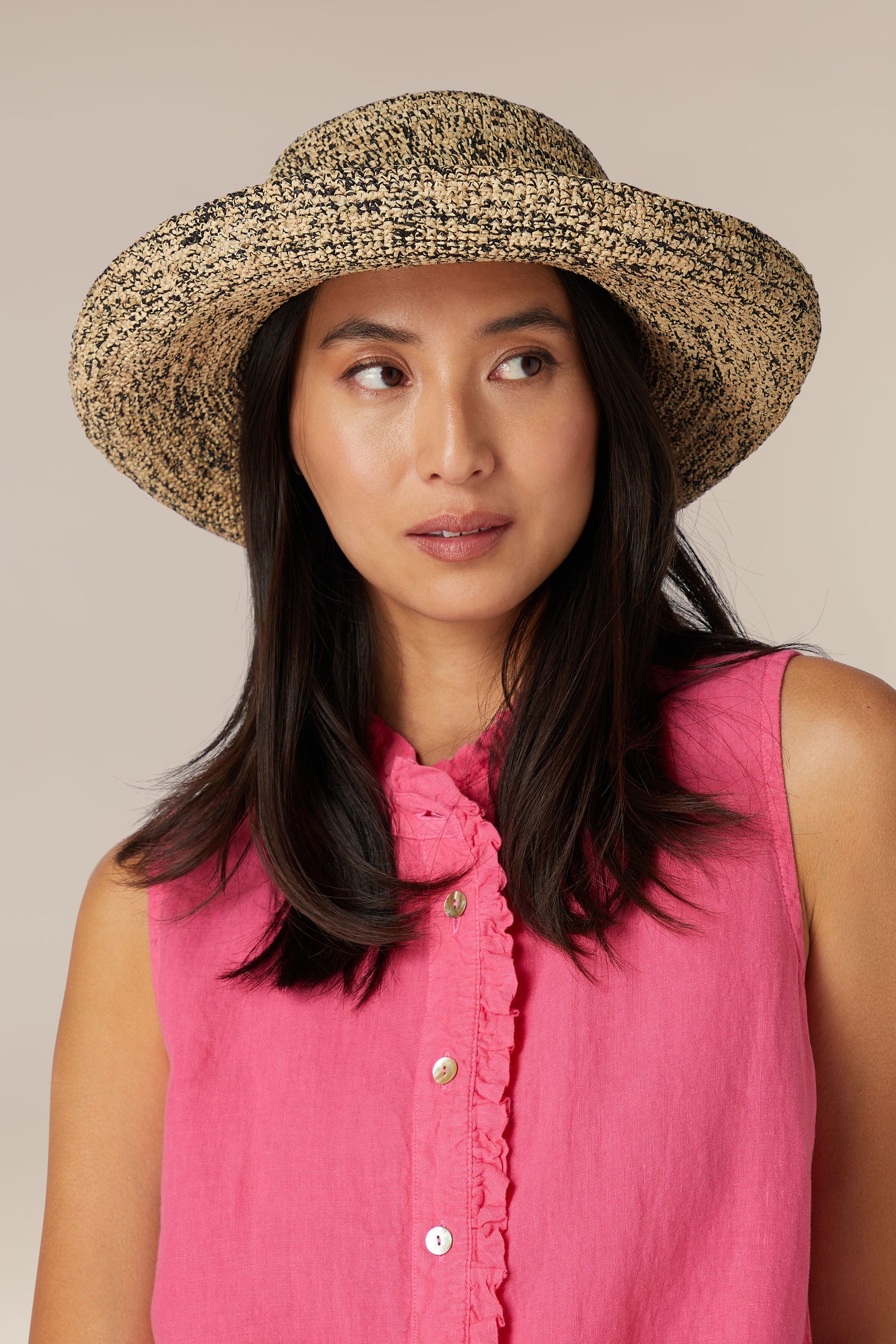 Woman in a pink blouse wearing a Wide Brim Woven Raffia Hat from Madagascar.