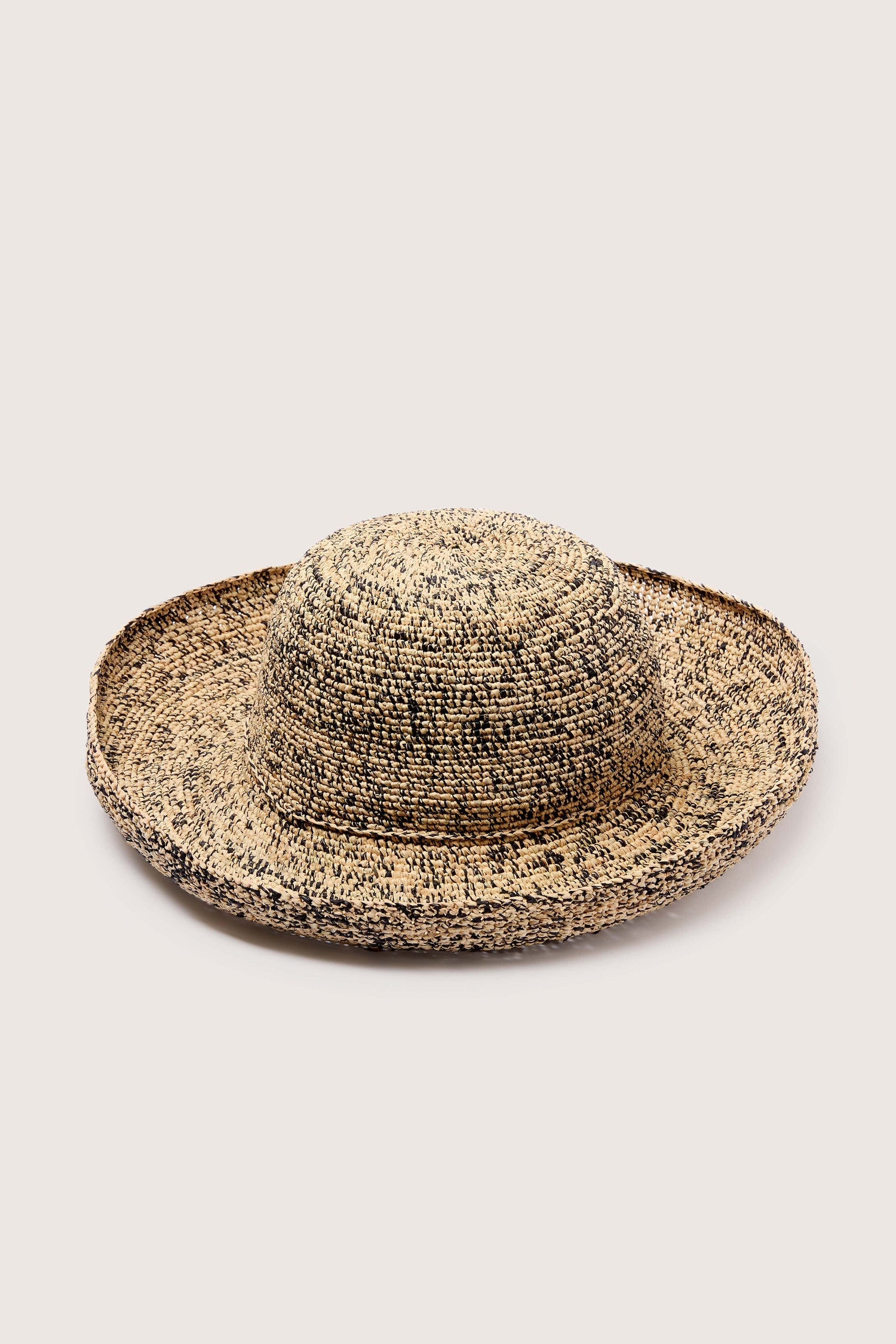 A Wide Brim Woven Raffia Hat from Madagascar against a neutral background.