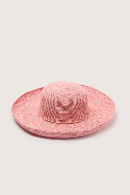 A pink Wide Brim Woven Raffia Hat isolated on a white background.