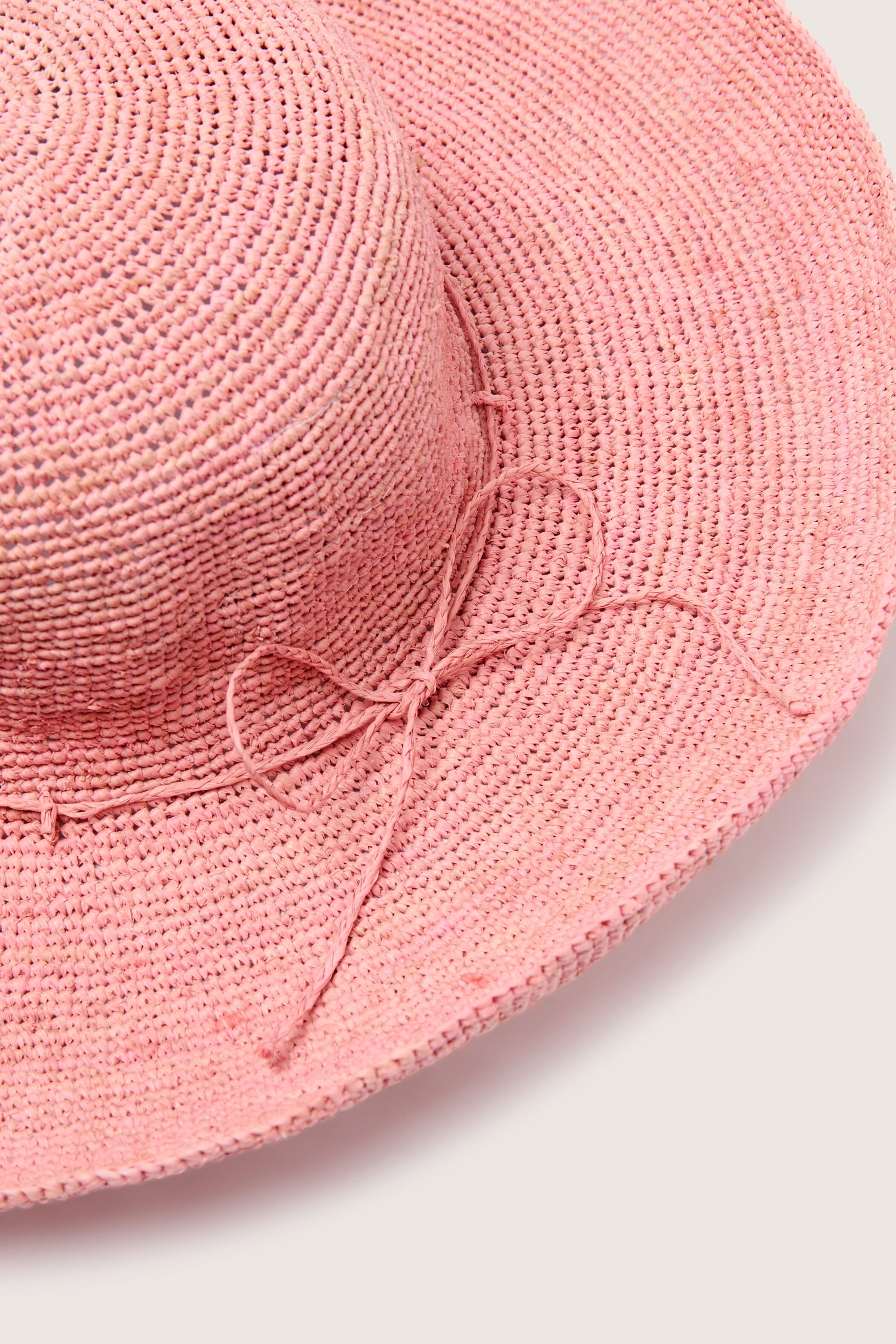 Close-up of a Madagascar Wide Brim Woven Raffia Hat with a bow detail.