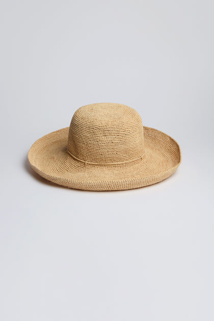 The Handwoven Wide Brim Raffia Hat sits elegantly on a plain white background, offering stylish sun protection.