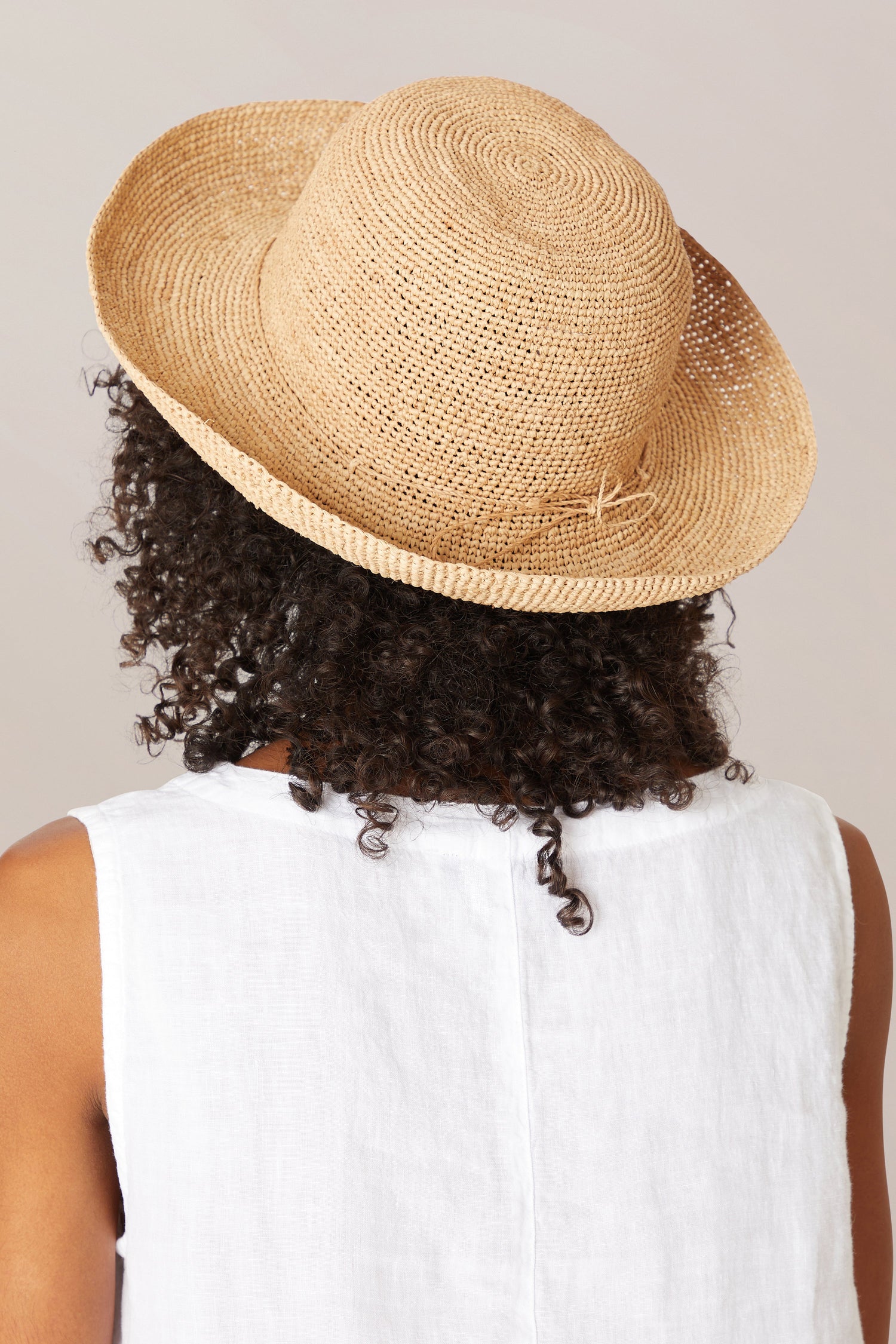 Person in a white top wearing a Raffia Hat, viewed from behind.