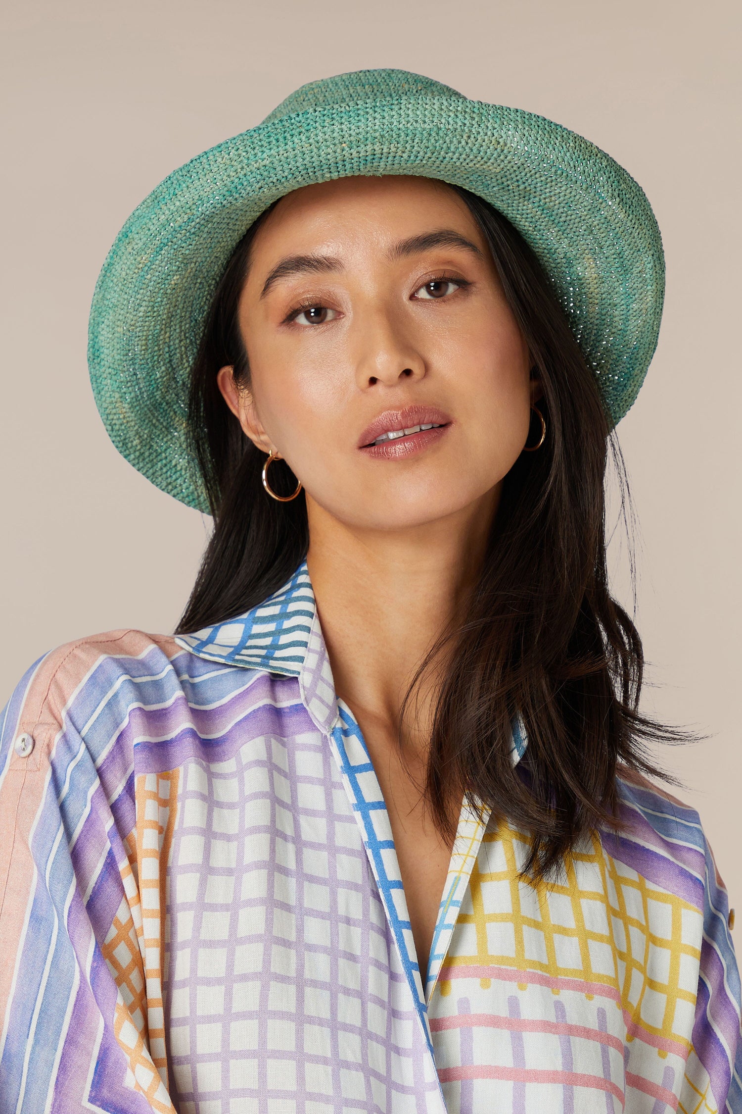 A woman wearing a striped shirt and a lightweight breathable Woven Raffia Hat.