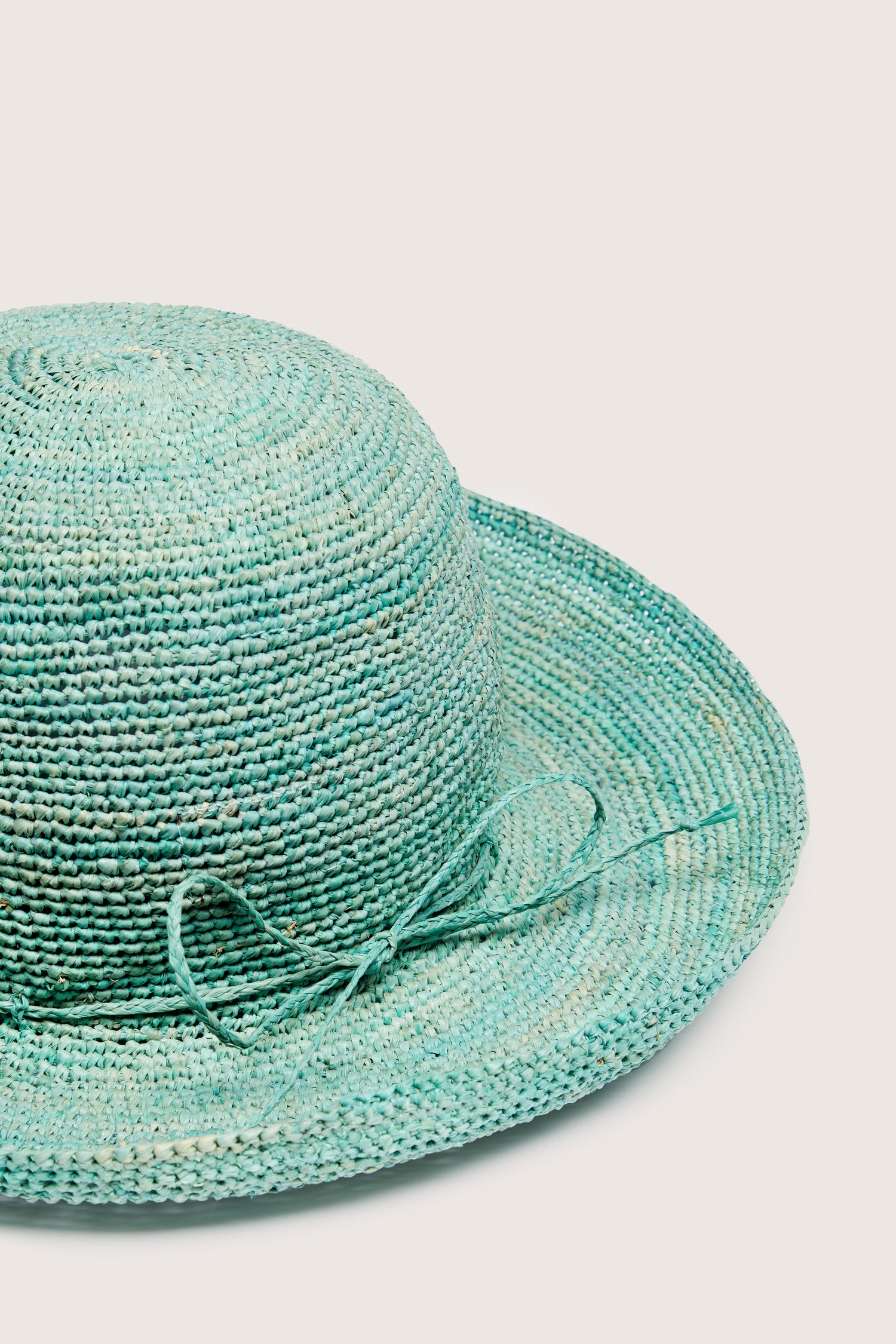 A woven raffia hat with a bow on a white background.