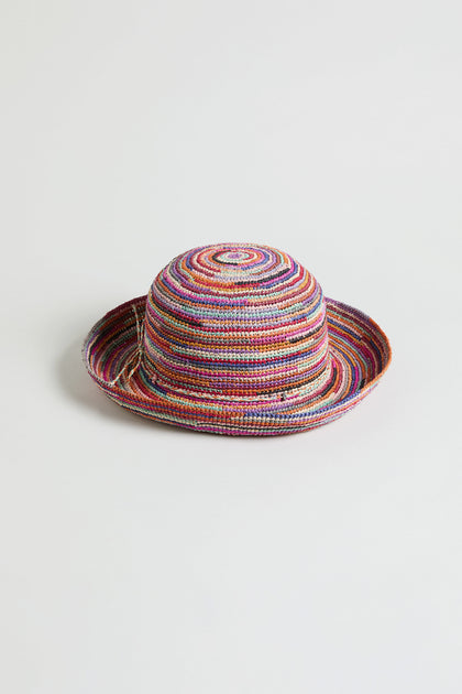 The Handwoven Rainbow Raffia Hat, crafted by artisans in Madagascar, showcases a multicolored design with a round crown and upturned brim, displayed against a plain white background.