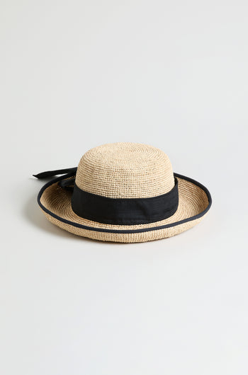 The Handwoven Raffia Ribbon Hat features a wide black ribbon band and bow, expertly crafted with a wide brim and displayed against a plain light background.