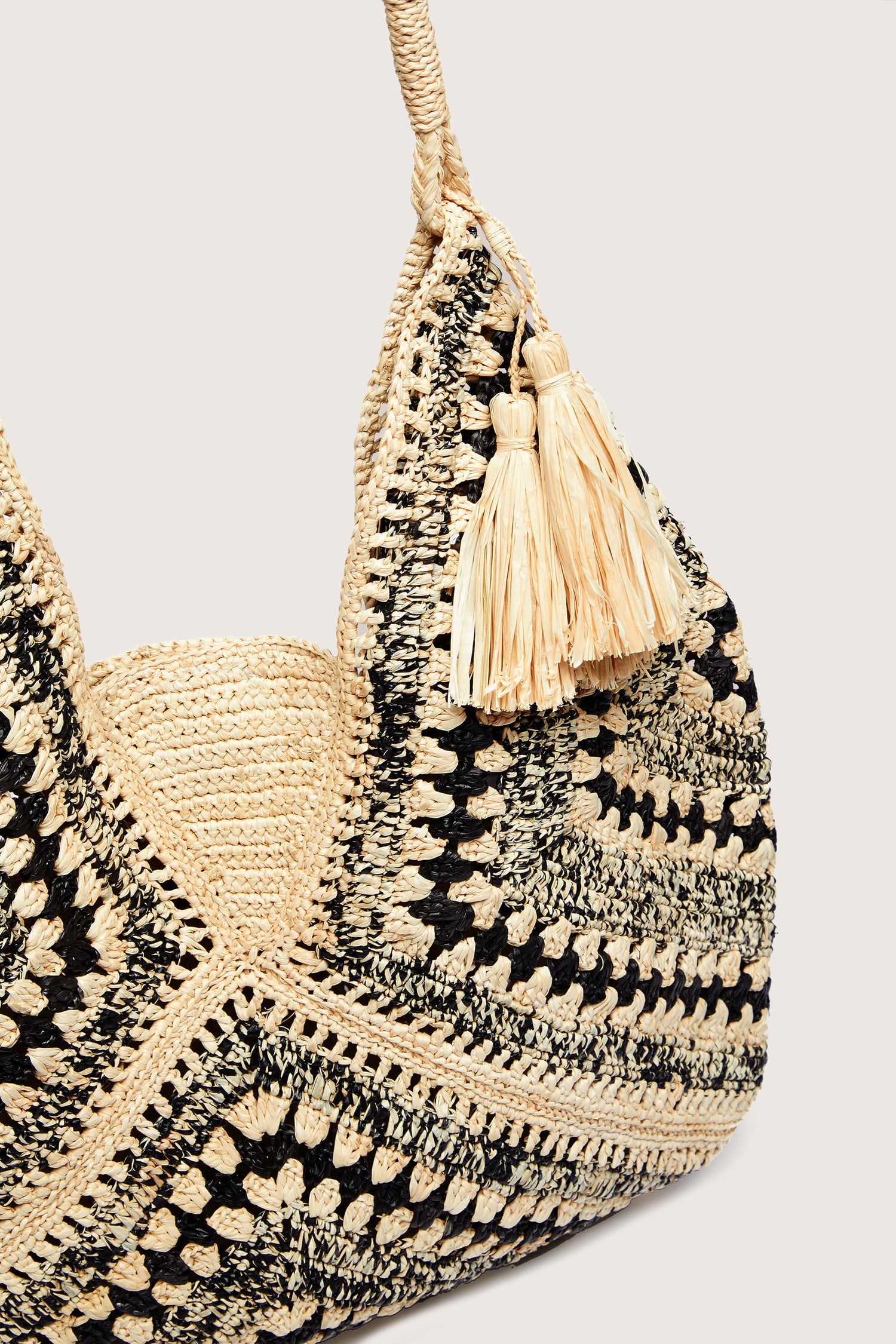 Frida Woven Bohemian Raffia Bag with black and natural patterns and a tassel detail.