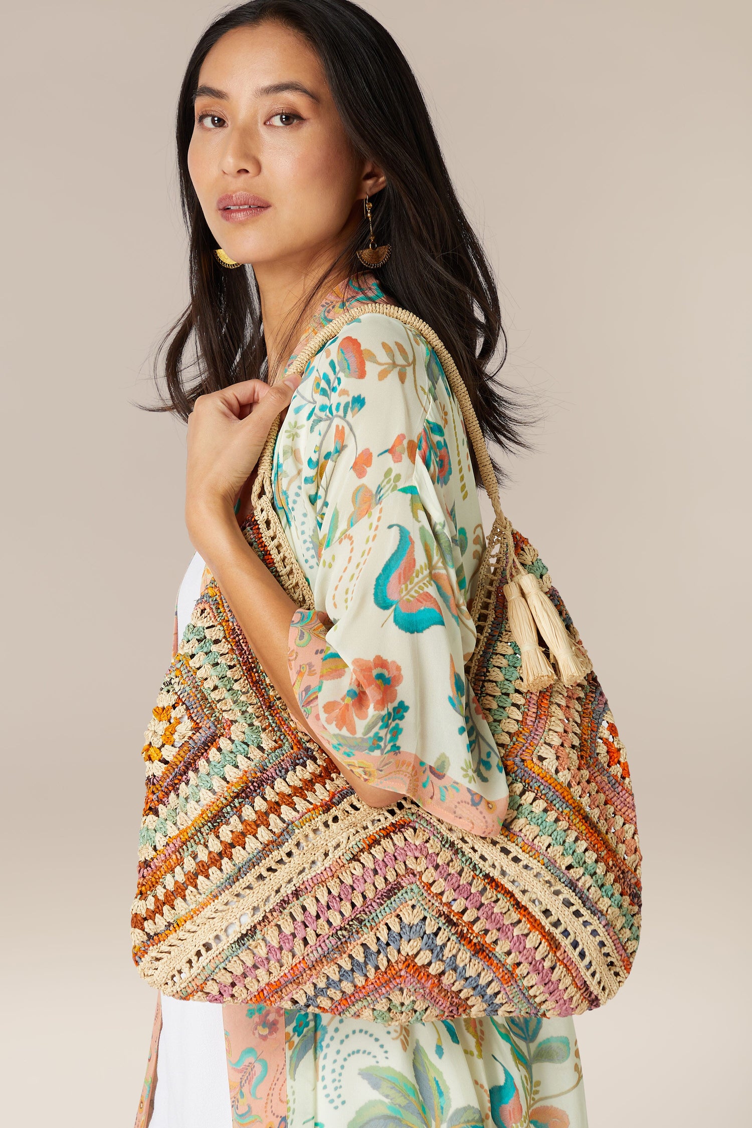 A woman modeling a patterned dress and carrying a colorful Woven Bohemian Raffia Bag.