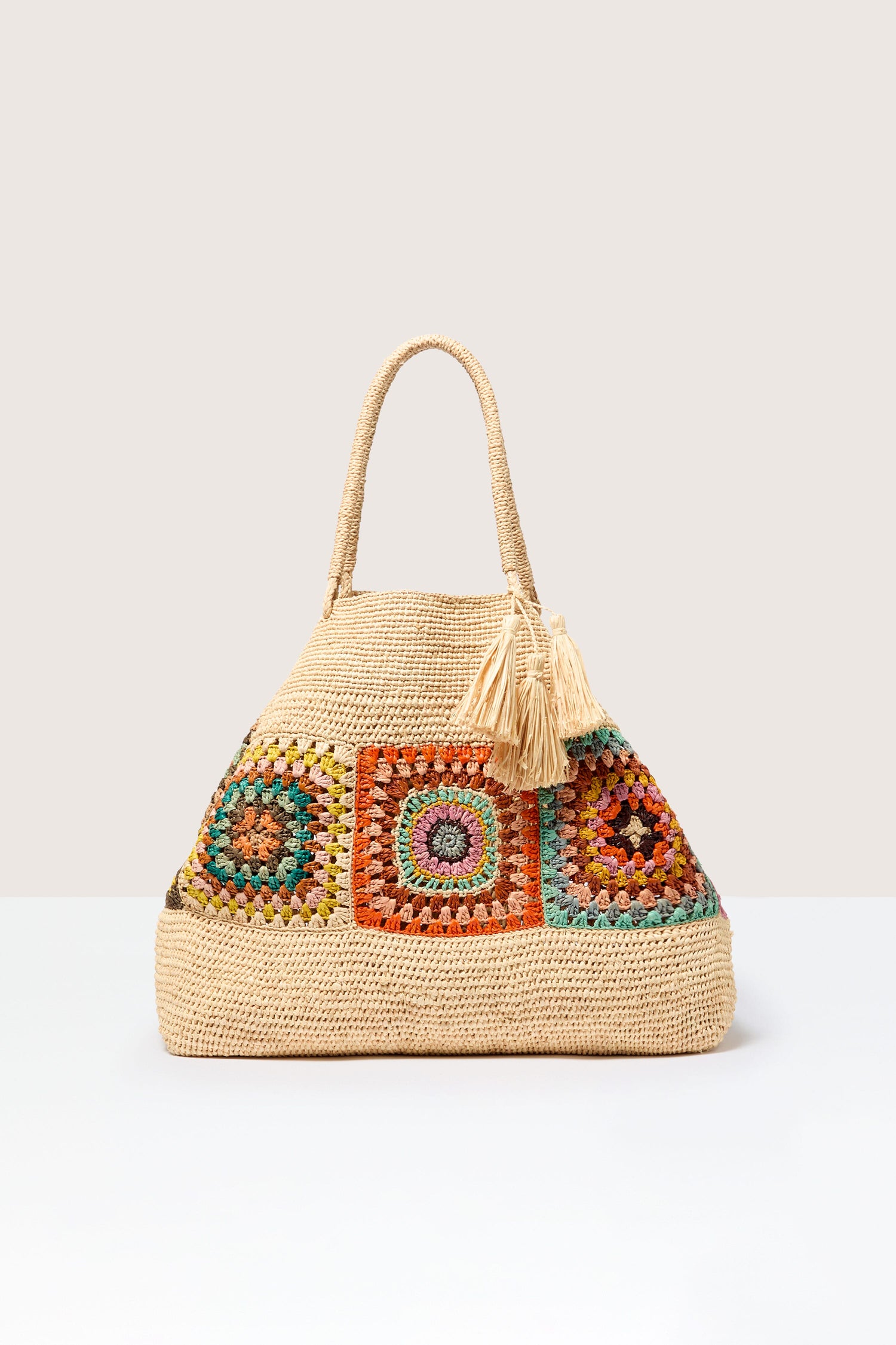 Aztec Woven Raffia Bag with colorful embellishments and a tassel detail, displayed against a neutral background.