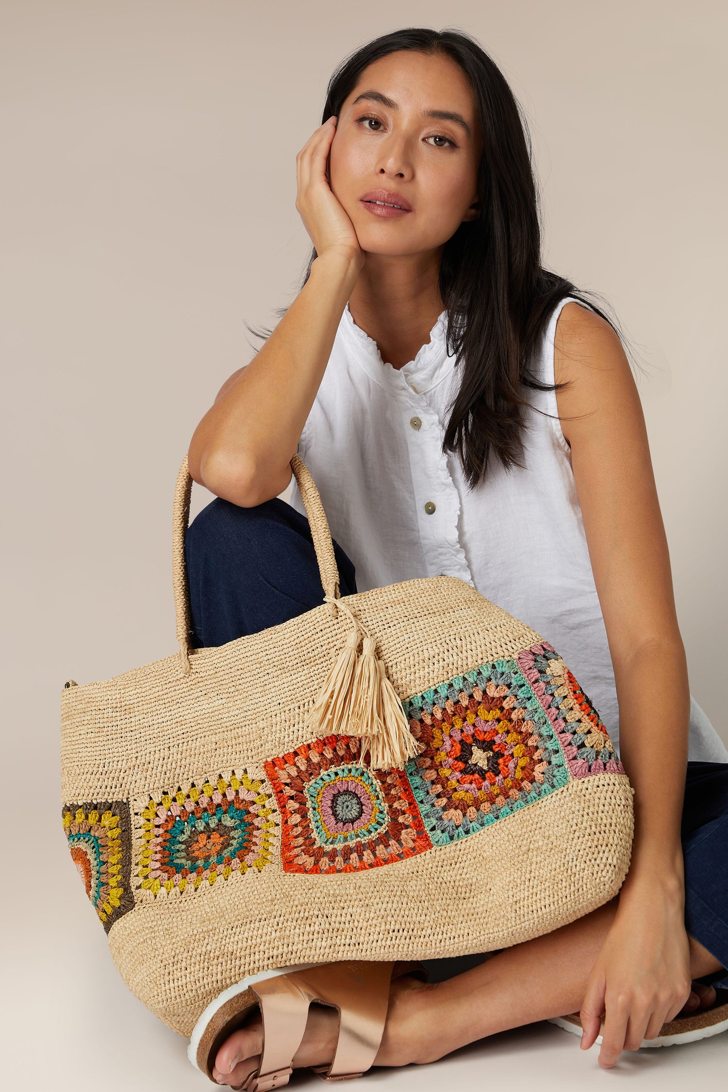 A woman sitting with a colorful Aztec woven Raffia Bag.