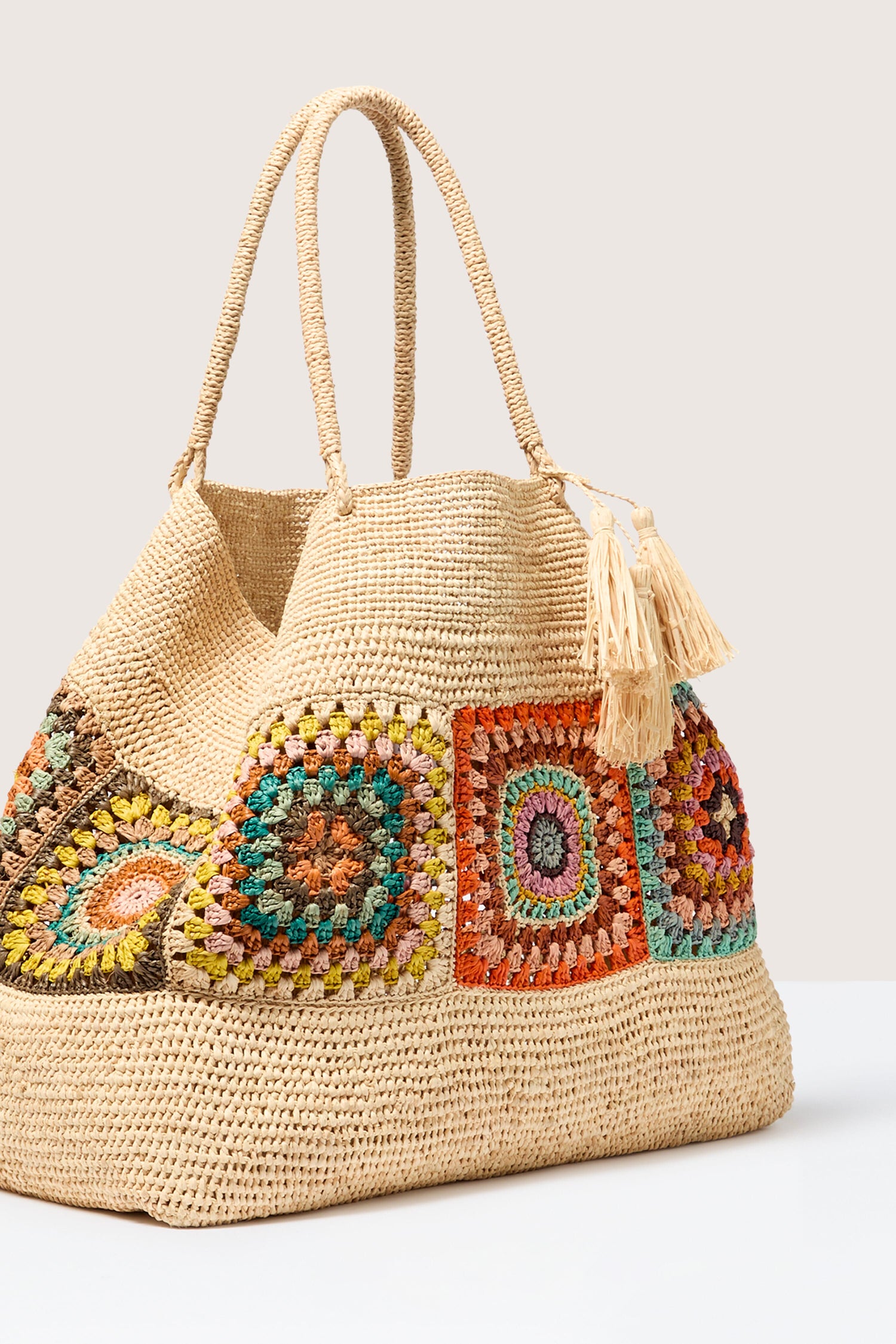 Handcrafted Aztec woven raffia bag with colorful embroidered patterns and a tassel decoration from Madagascar.