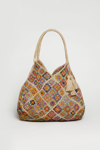 The Handwoven Flower Raffia Bag features multicolored crochet granny square patterns, two rope handles, and beige tassel accents—expertly crafted by Madagascar artisans and showcased on a plain white background.