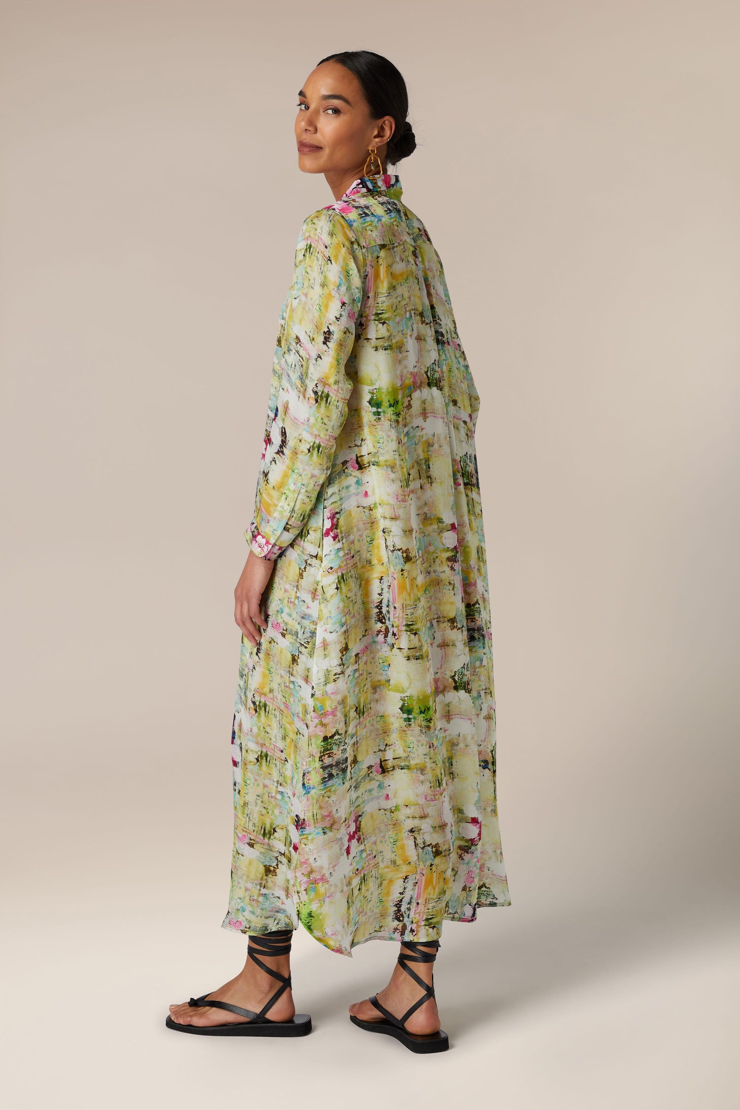 The back view of a woman wearing a green and yellow printed Pelia Button Front Dress.