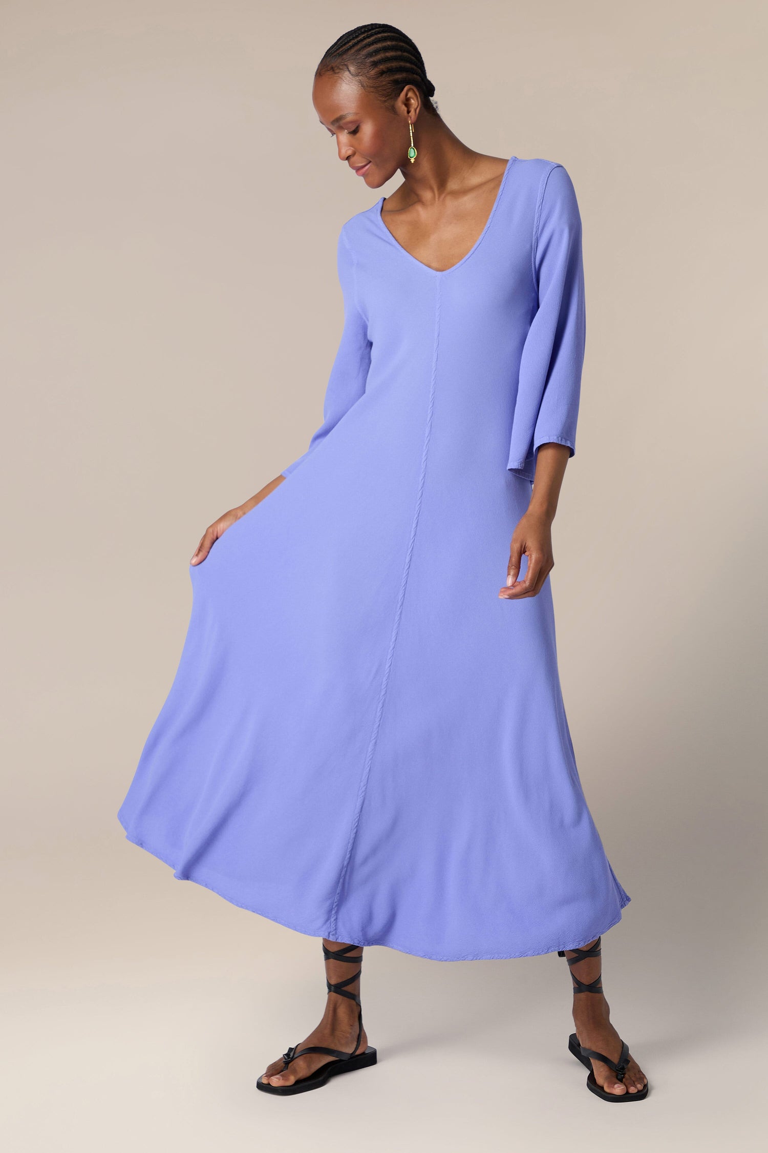 Woman twirling in a stylish blue Crepe Maxi Dress with a v-neckline and sandals.