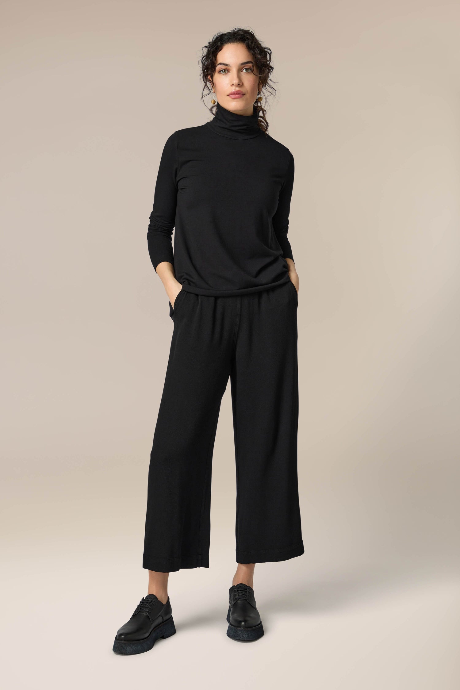 A woman wearing Crepe Wide Trousers with an elasticated waist.