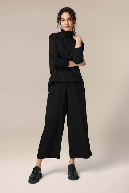 A woman donning Crepe Wide Trouser with an elasticated waist.