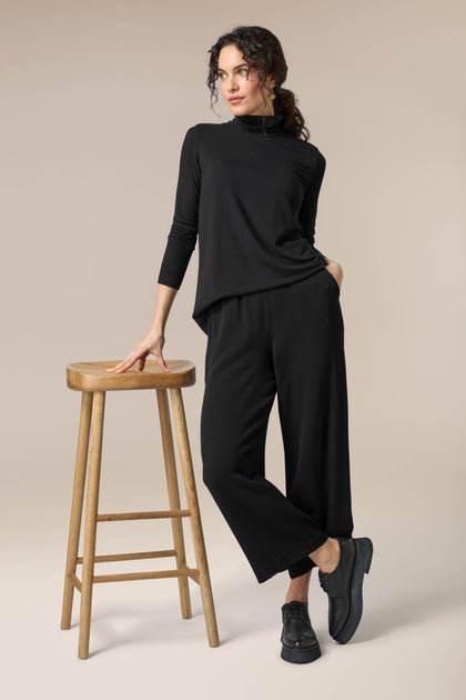 A woman wearing versatile crepe wide trousers with an elasticated waist and a turtle neck top.