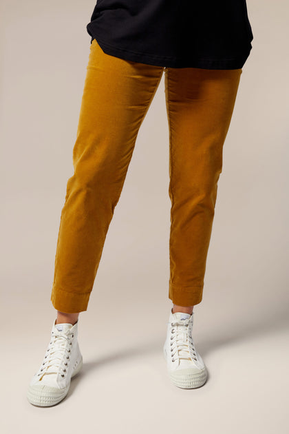 A woman wearing a black t-shirt and mustard corduroy pants with a velvety Cotton Moleskin Slim Trouser finish.