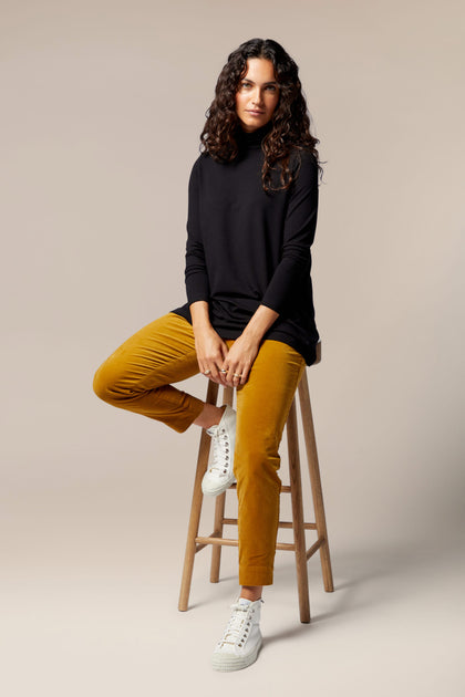A woman sitting on a stool in Cotton Moleskin Slim Trousers.