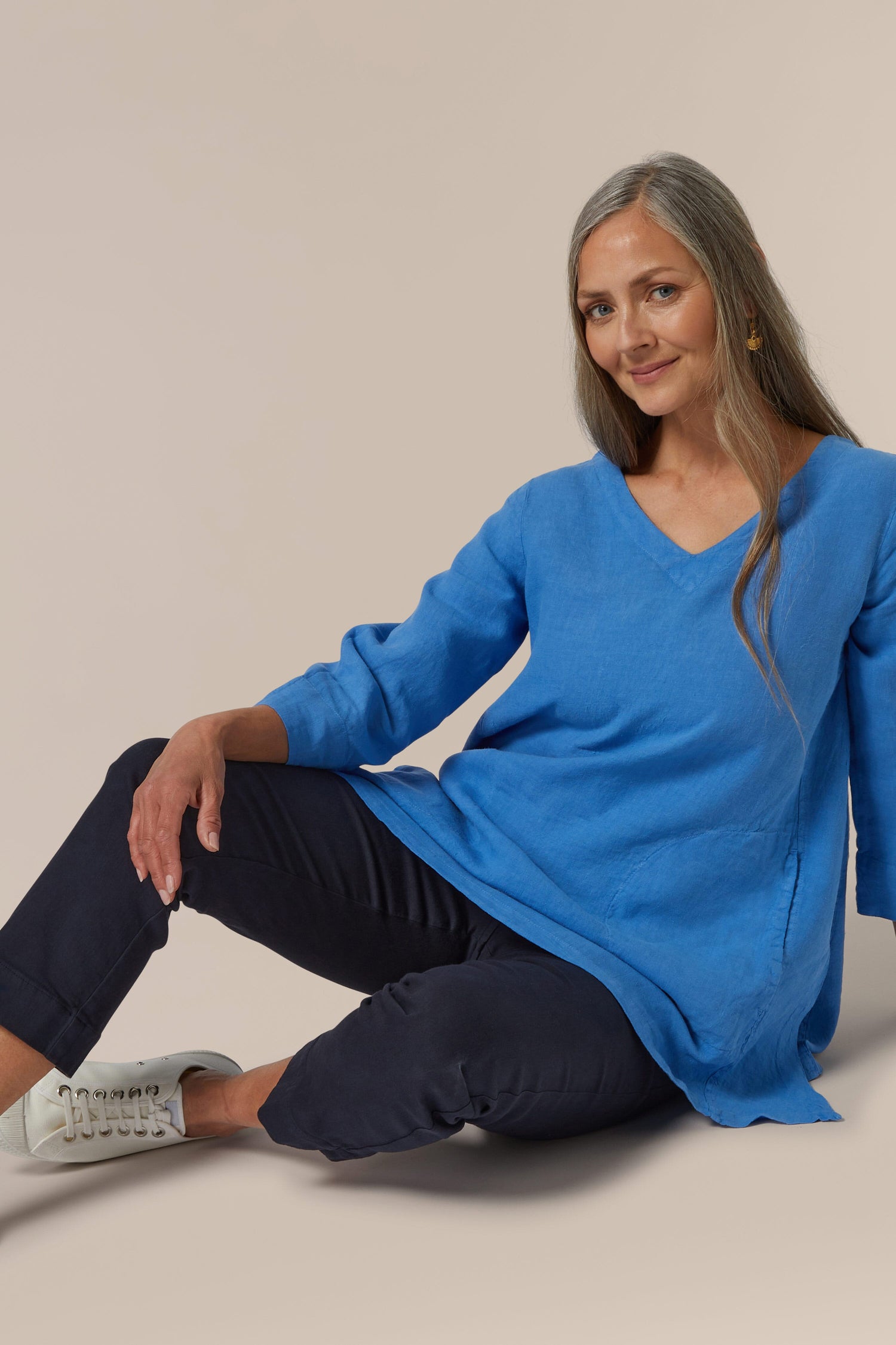 Woman in a blue top and navy Stretch Cotton Slim Crop Trouser sitting against a neutral background.