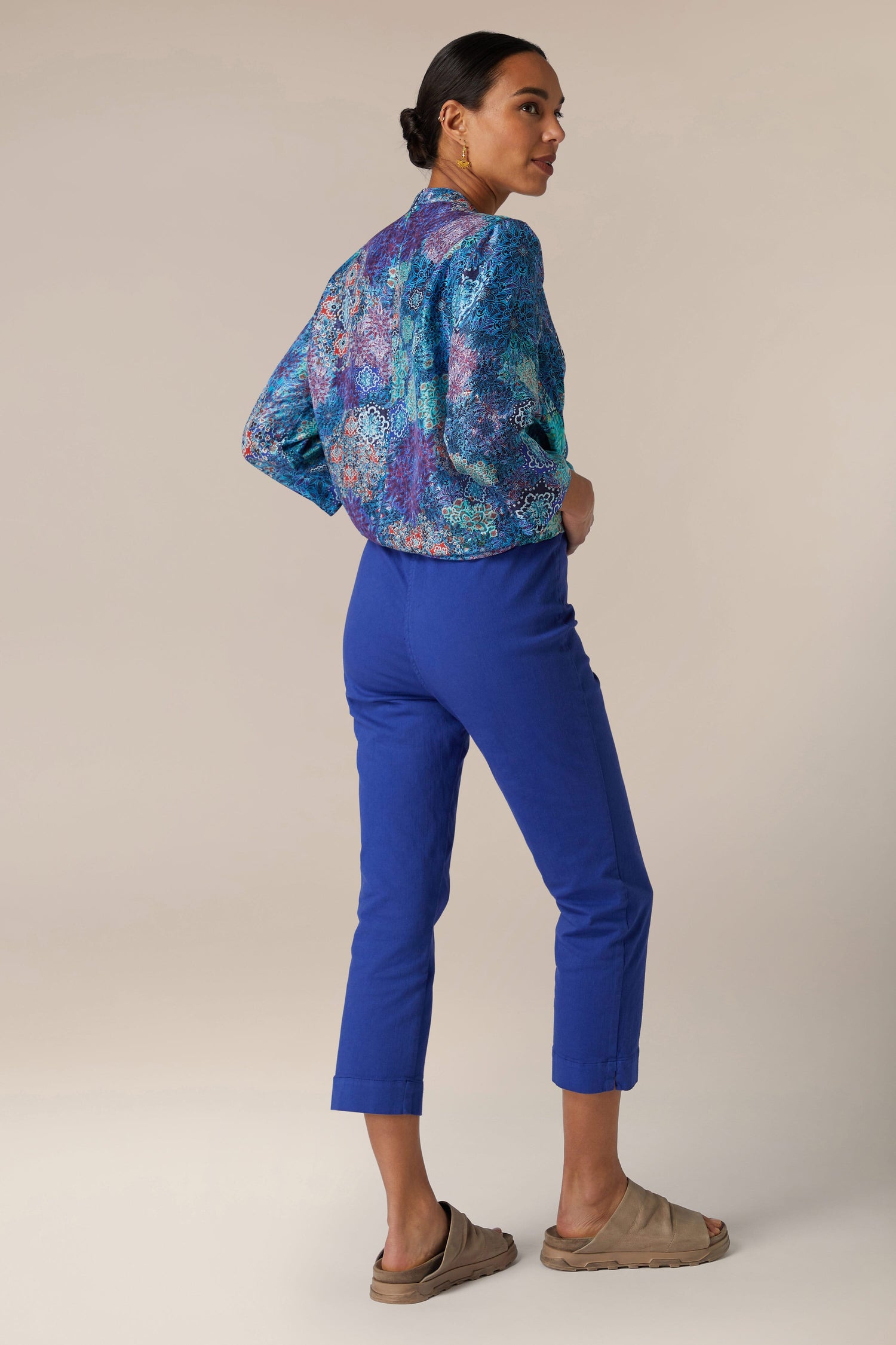 Woman posing in a colorful blouse and blue Stretch Cotton Slim Trousers against a neutral background.