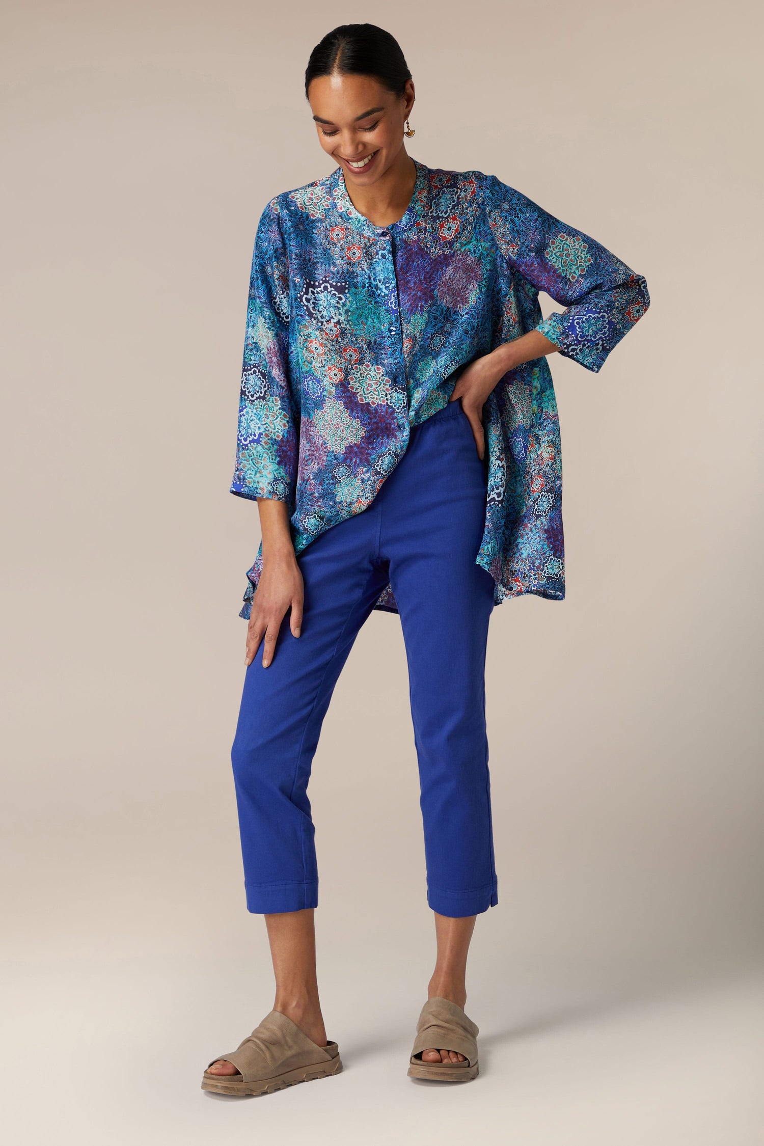 A woman in a blue printed blouse and blue Stretch Cotton Slim Trousers posing with one hand on her hip.