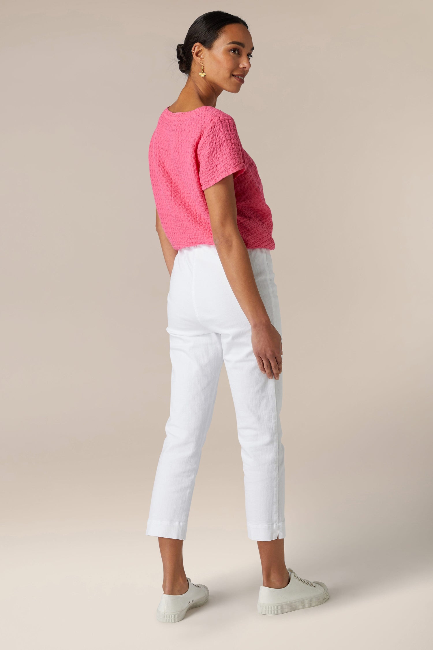 Woman wearing a pink top and Stretch Cotton Slim Trousers standing in a neutral pose against a beige background.